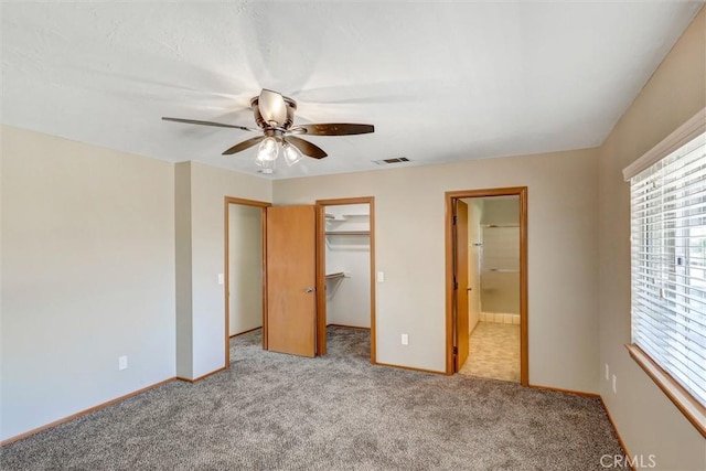 unfurnished bedroom with ceiling fan, light colored carpet, a walk in closet, and a closet