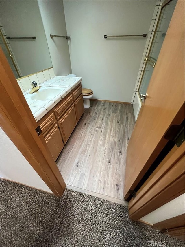 bathroom with vanity, hardwood / wood-style flooring, toilet, and a shower with door