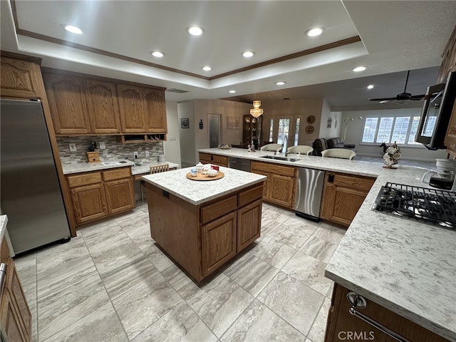 kitchen with a raised ceiling, a center island, and black appliances