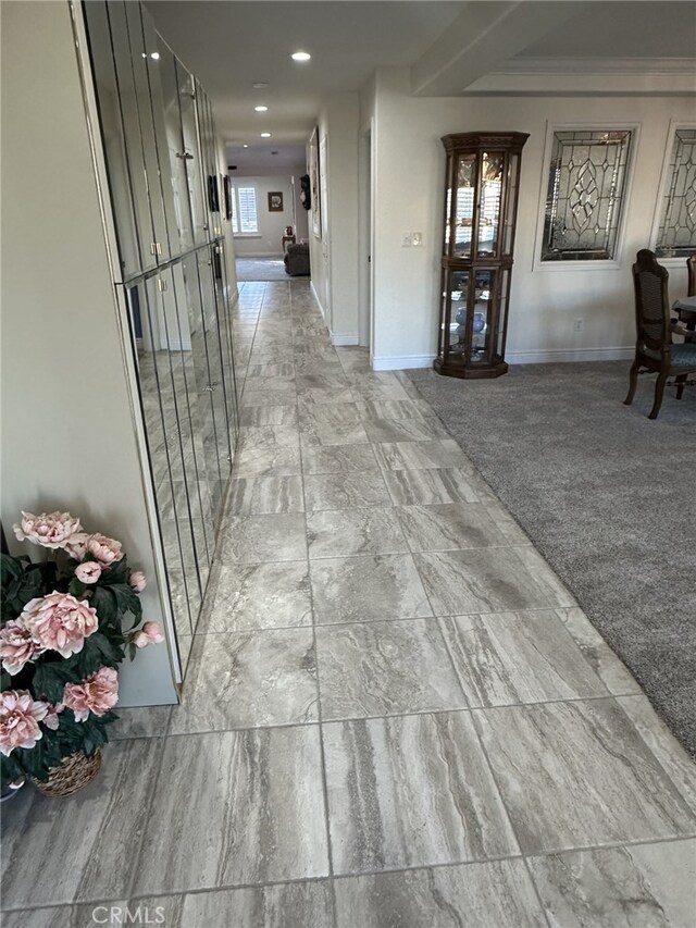 corridor with crown molding and light colored carpet