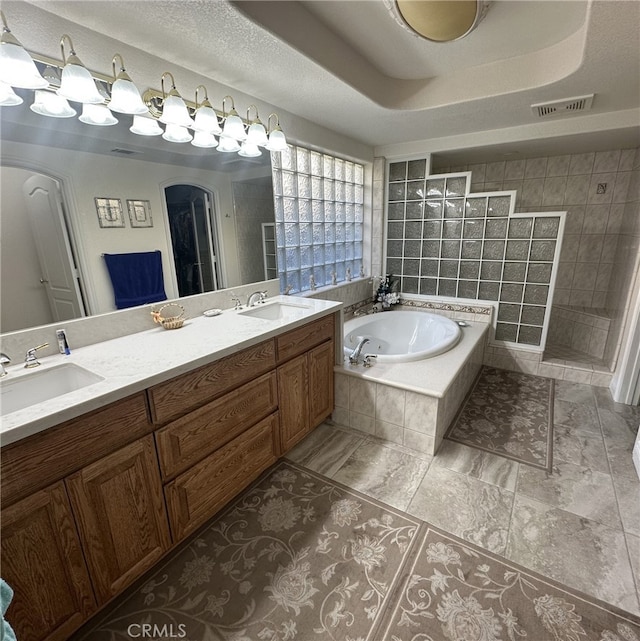 bathroom with vanity, a textured ceiling, plus walk in shower, and a tray ceiling