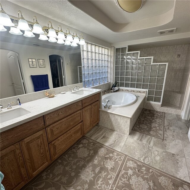 bathroom featuring vanity, plus walk in shower, a textured ceiling, and a tray ceiling