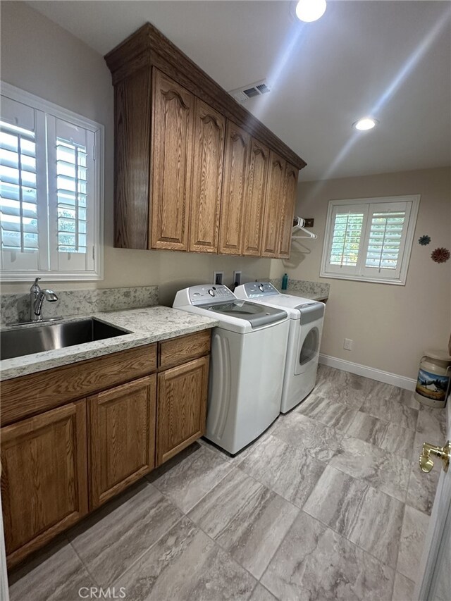 clothes washing area featuring sink, cabinets, plenty of natural light, and independent washer and dryer