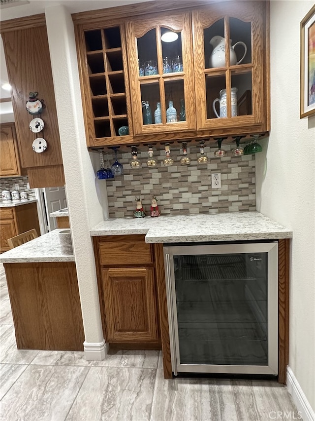 bar with beverage cooler, light stone countertops, and backsplash