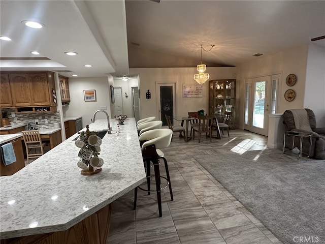 16232 Ridge View Dr, Apple Valley, CA 92307 - kitchen featuring a sink, a breakfast bar, brown cabinetry, decorative backsplash, and a chandelier