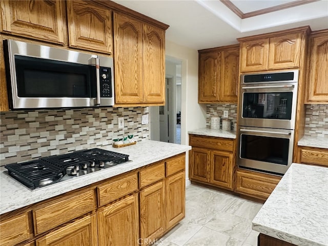 16232 Ridge View Dr, Apple Valley, CA 92307 - kitchen featuring appliances with stainless steel finishes, tasteful backsplash, light countertops, brown cabinetry, and a raised ceiling
