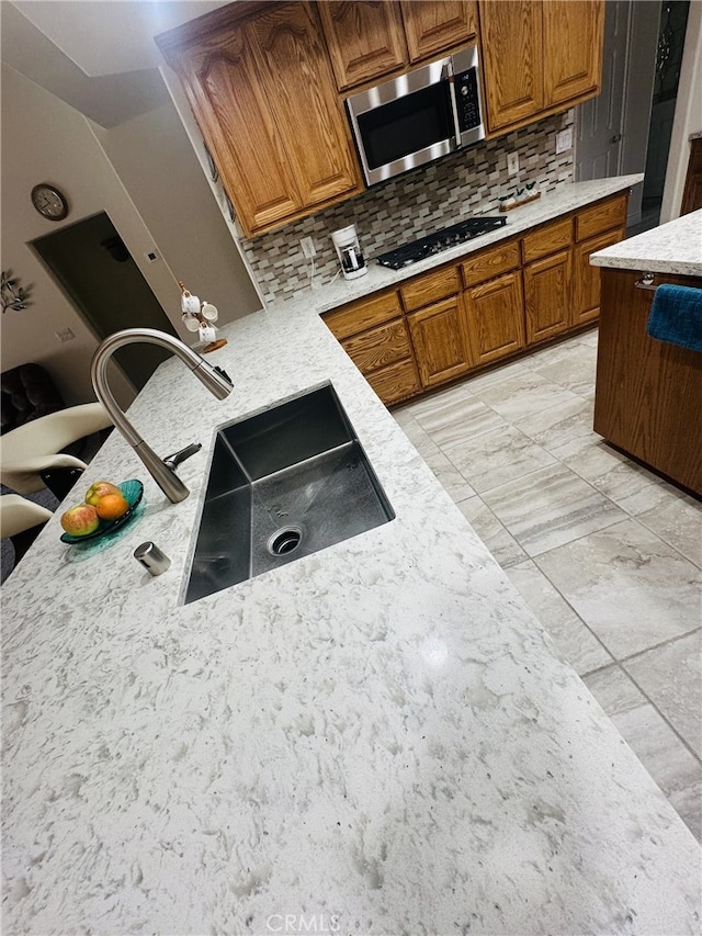 16232 Ridge View Dr, Apple Valley, CA 92307 - kitchen featuring stainless steel microwave, brown cabinetry, tasteful backsplash, a sink, and gas stovetop