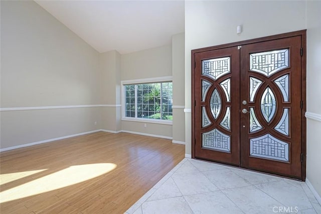 foyer with french doors, vaulted ceiling, and light tile patterned floors