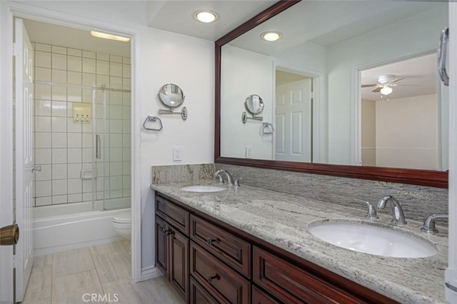 full bathroom featuring toilet, vanity, ceiling fan, and tiled shower / bath