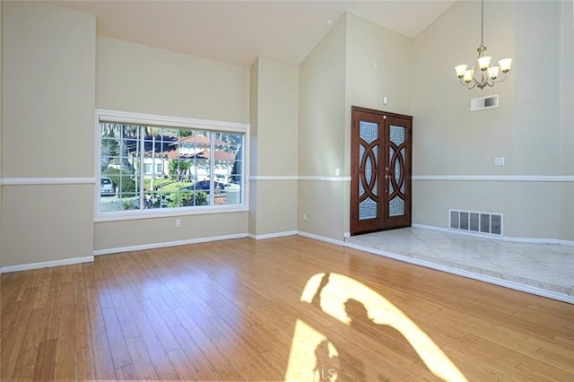 entryway with a notable chandelier, hardwood / wood-style floors, and high vaulted ceiling