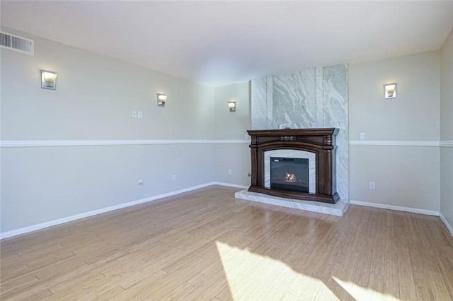 unfurnished living room with a high end fireplace and light hardwood / wood-style flooring