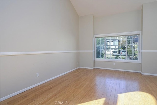 spare room with lofted ceiling and light hardwood / wood-style flooring