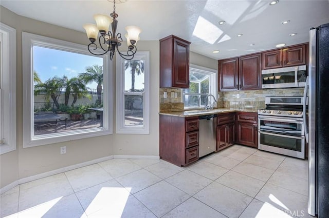 kitchen with stainless steel appliances, hanging light fixtures, light tile patterned floors, a notable chandelier, and backsplash