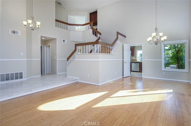 entrance foyer featuring a high ceiling, a notable chandelier, and light hardwood / wood-style floors