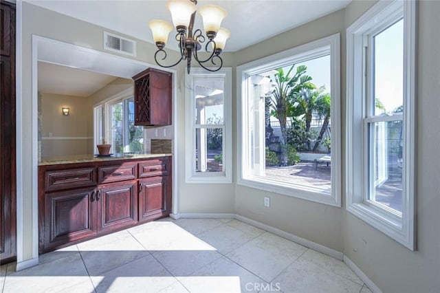 kitchen featuring a wealth of natural light, light stone countertops, light tile patterned floors, and a chandelier