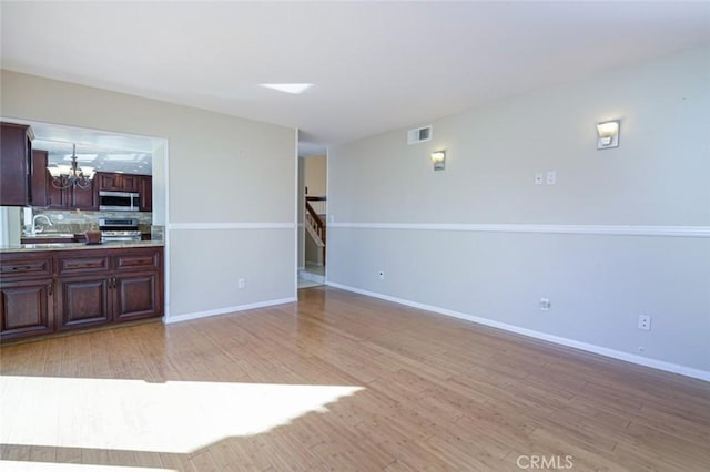 living room with sink, an inviting chandelier, and light hardwood / wood-style floors