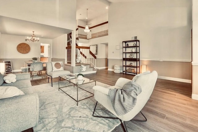 living room featuring a towering ceiling, hardwood / wood-style flooring, and an inviting chandelier