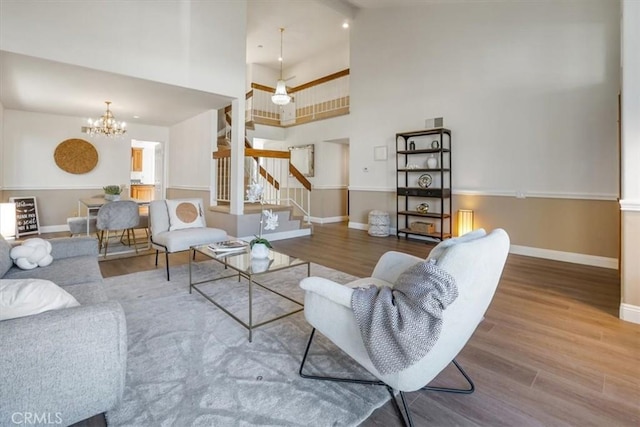 living room featuring a high ceiling, a chandelier, and wood-type flooring