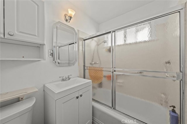 full bathroom featuring toilet, combined bath / shower with glass door, and vanity