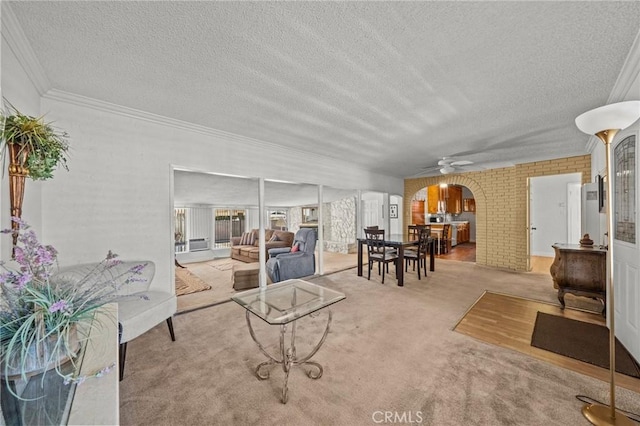 living room with ceiling fan, light colored carpet, a textured ceiling, and ornamental molding