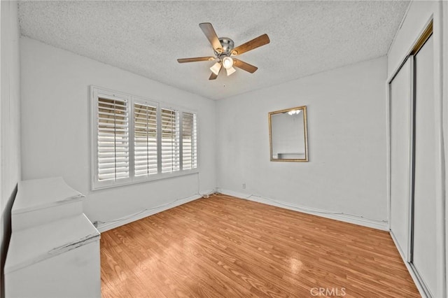 unfurnished bedroom featuring a textured ceiling, ceiling fan, and light hardwood / wood-style flooring