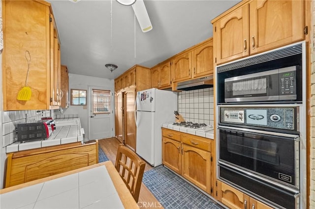 kitchen with tile countertops, decorative backsplash, and white appliances