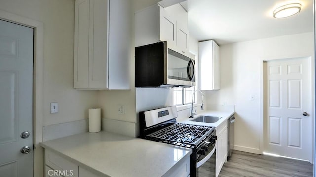 kitchen with sink, stainless steel appliances, light wood-type flooring, and white cabinetry