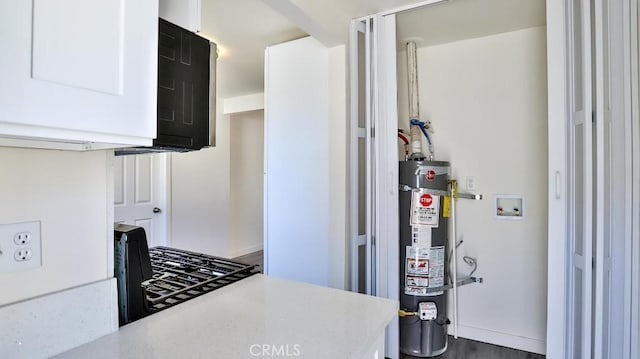 kitchen featuring water heater and white cabinets