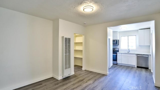 interior space with a textured ceiling, sink, and hardwood / wood-style flooring