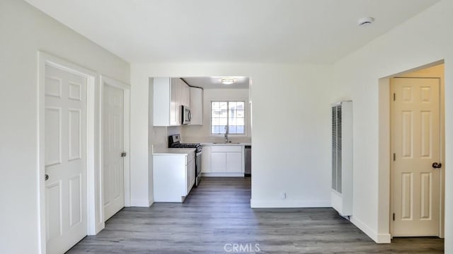 kitchen with stainless steel appliances, white cabinetry, and dark wood-type flooring