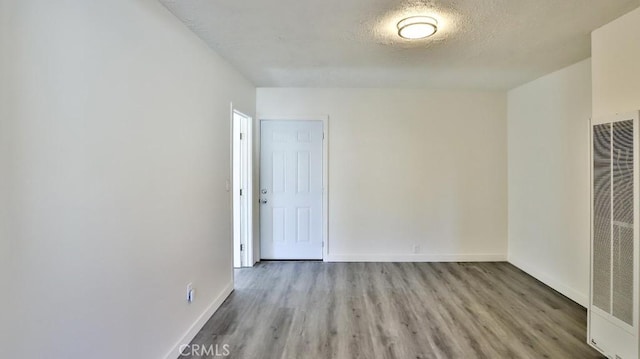 spare room featuring a textured ceiling and light hardwood / wood-style floors