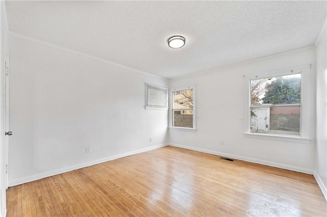 spare room featuring plenty of natural light, crown molding, and light hardwood / wood-style flooring