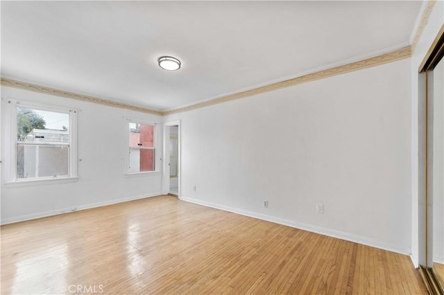 empty room with ornamental molding and light wood-type flooring