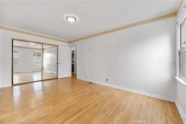 unfurnished bedroom with light wood-type flooring, a closet, and crown molding