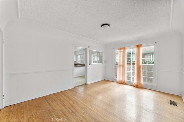 unfurnished room featuring light wood-type flooring and a textured ceiling