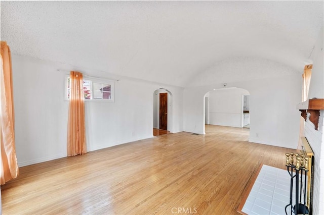 unfurnished living room with brick ceiling, lofted ceiling, and light hardwood / wood-style flooring