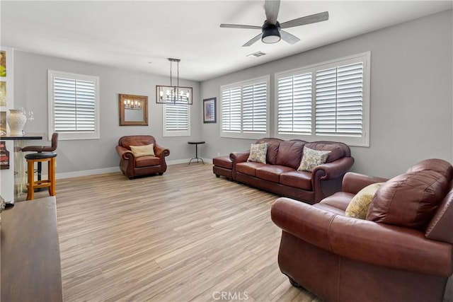 living room with ceiling fan with notable chandelier and light hardwood / wood-style flooring