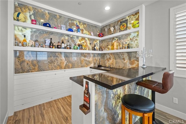 bar featuring wood-type flooring, white cabinetry, and sink