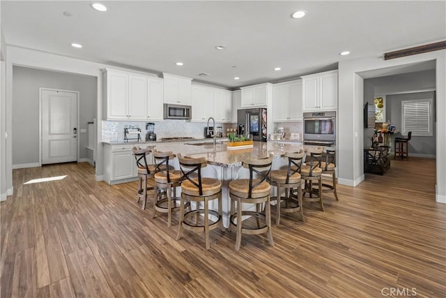 kitchen with light stone counters, sink, white cabinets, and stainless steel appliances