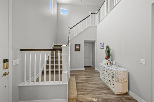 stairway featuring a towering ceiling and hardwood / wood-style flooring