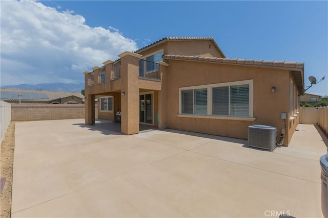 rear view of house with a mountain view, a patio, a balcony, and central AC