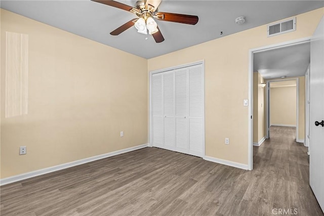 unfurnished bedroom with wood-type flooring, a closet, and ceiling fan