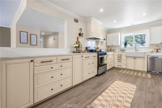 kitchen with light wood-type flooring, appliances with stainless steel finishes, decorative backsplash, and sink