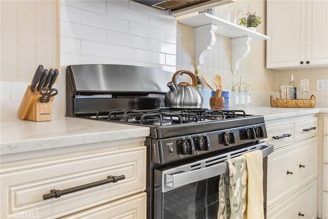 kitchen with light stone countertops, decorative backsplash, ventilation hood, and stainless steel range with gas stovetop