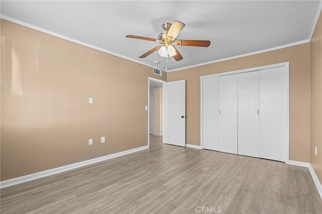 unfurnished bedroom featuring light hardwood / wood-style floors, ceiling fan, crown molding, and a closet