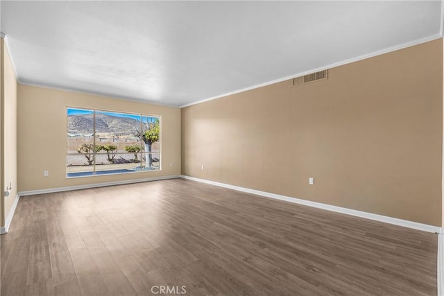 empty room featuring dark wood-type flooring and crown molding