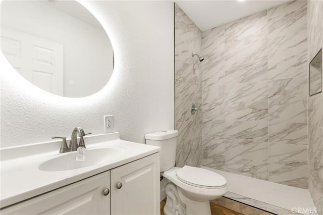 bathroom featuring vanity, toilet, and a tile shower