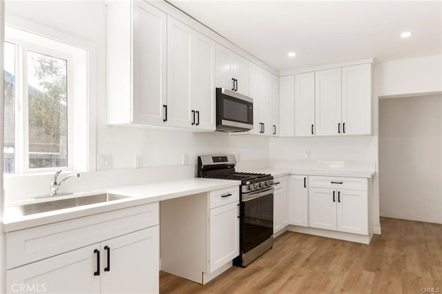 kitchen with stainless steel appliances, white cabinetry, and sink