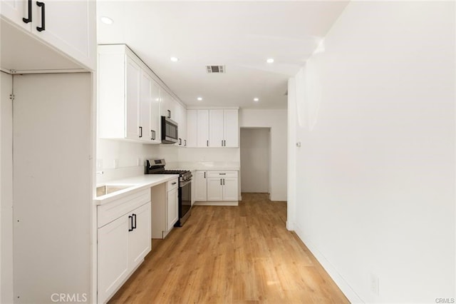 kitchen with light hardwood / wood-style floors, white cabinetry, sink, and appliances with stainless steel finishes