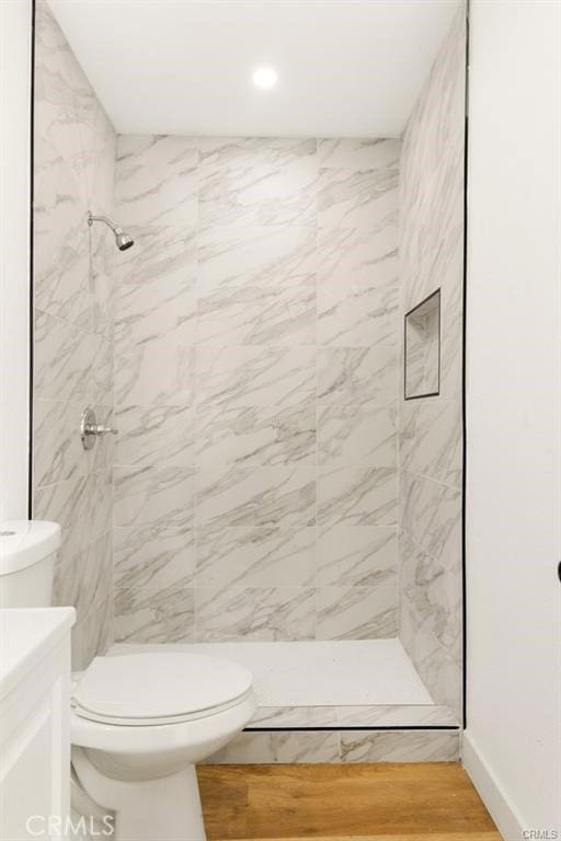 bathroom featuring a tile shower, vanity, and toilet